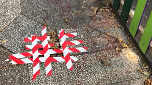 Baldosas rotas y agarradas con cinta aislante junto a una zona de juegos infantiles en el centro de la ciudad