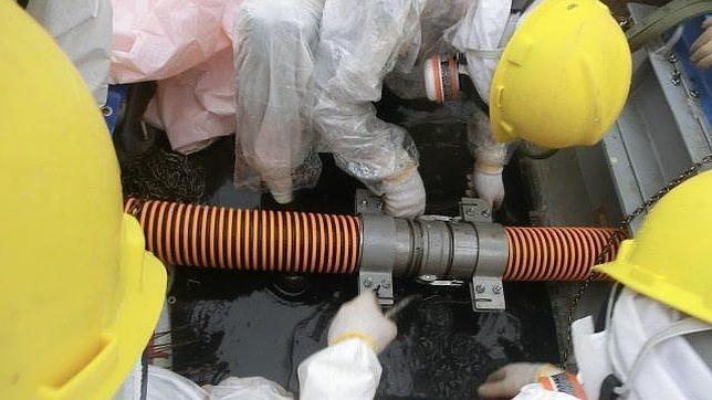 Trabajadores de la central de Fukushima con trajes de protección mientras reparan una fuga de aguas