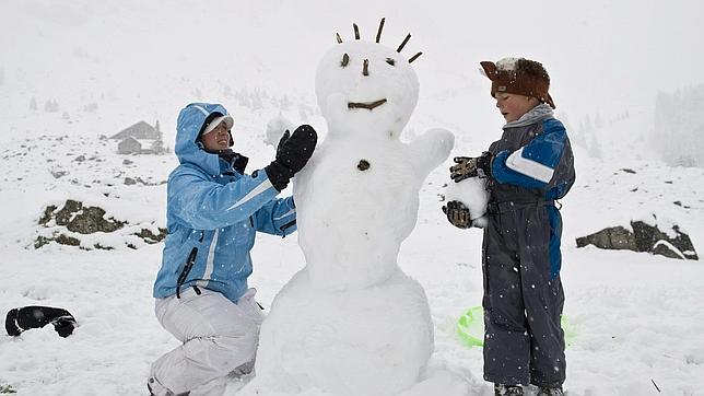 Dos niños dan forma a un muñeco de nieve