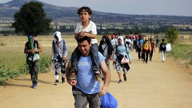 Un inmigrante lleva a hombros a un niño mientras camina hacia Presevo, en Serbia