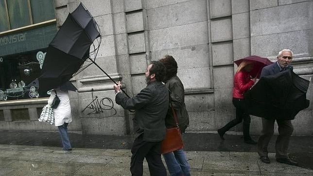 Los madrileños luchan contra el viento y la lluvia en la Gran Vía