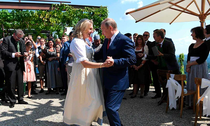 A la izq., Vladimir Putin brinda durante un acto de reconocimiento a los militares que combatieron en Siria, en 2017. A la dcha., baila con la ministra de Exteriores de Austria, Karin Kneissl, en 2018.
