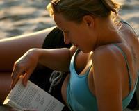 Una mujer lee muy relajada en la playa. /ARCHIVO