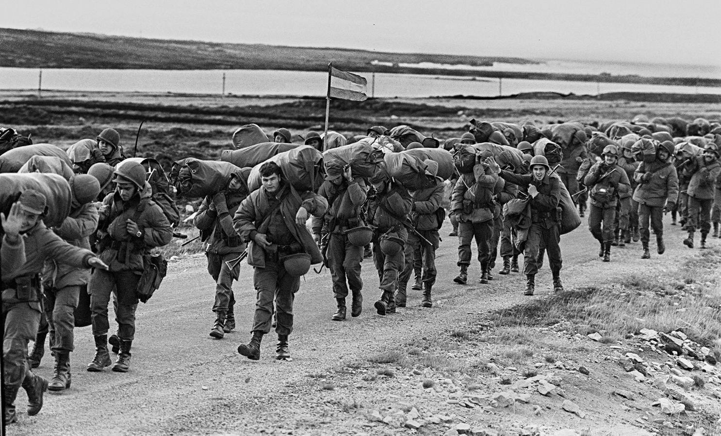 Soldados argentinos caminan el 13 de abril de 1982 para ocupar la base de los Marines Reales capturados en Puerto Argentino/Stanley, unos días después de que la dictadura militar argentina se apoderase de las islas Malvinas, comenzando una guerra entre Argentina y Reino Unido. 
