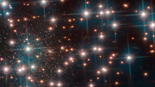 La imagen del Hubble muestra una parte del cúmulo globular NGC 6752. Detrás de las brillantes estrellas del cúmulo, se ve una colección más densa de estrellas débiles estrellas, una galaxia esferoidal enana desconocida hasta ahora