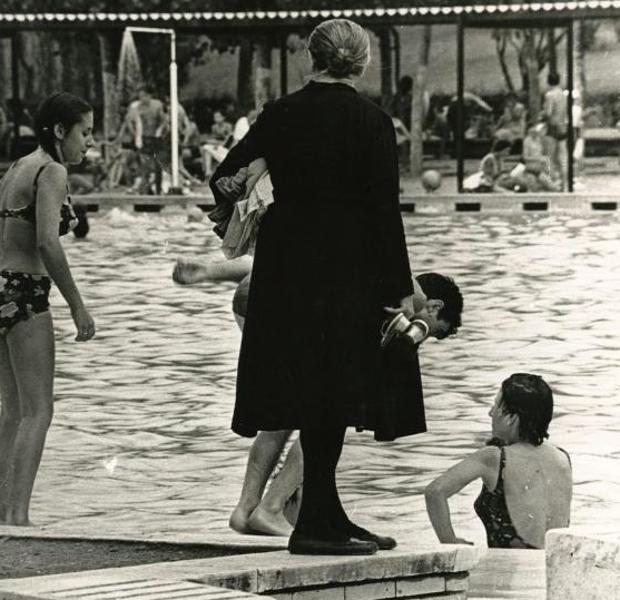 Una mujer vestida de negro en una piscina pública en el año 1968