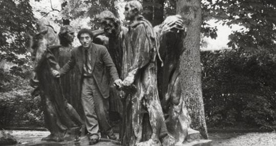 Alberto Giacometti en el parque de Eugène Rudier en Vésinet, posando junto a Les Bourgeois de Calais (Burgueses de Calais) de Rodin, 1950. © Fondation Giacometti, París