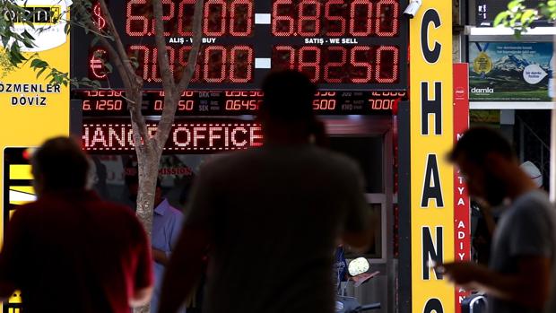 Ciudadanos pasean junto a un centro de cambio de divisas cuenta dólares americanos en Estambul, Turquía
