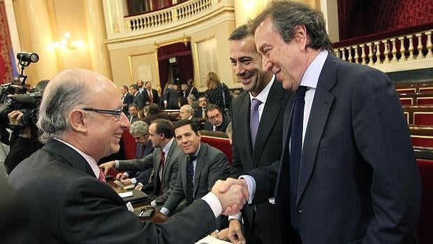 El consejero de Presidenci saluda al ministro de Hacienda durante la Comisión General de Comunidade