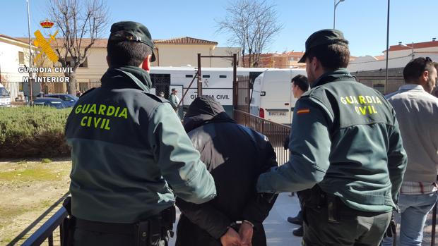 Uno de los detenidos, camino del furgón de la Guardia Civil para su traslado