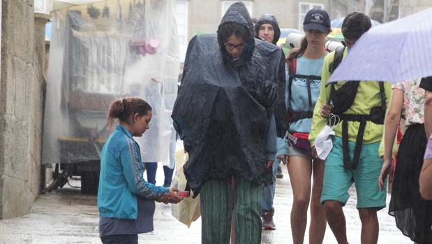 Una joven pide limosna bajo la lluvia, en Santiago