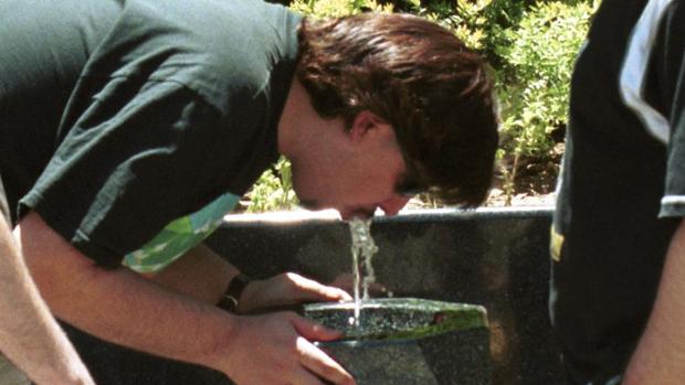Un joven, bebiendo en una fuente pública