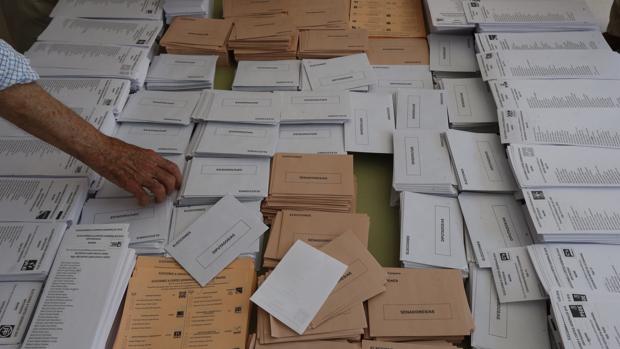 Un elector recoger una papeleta en una mesa electoral