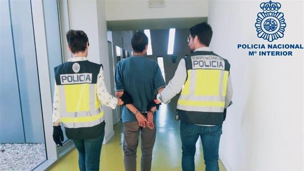 Dos agentes de la Policía Nacional llevan esposado al detenido