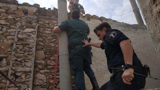 Dos guardias civiles y un policía local en el momento de sacar al bebé de la vivienda incendiada