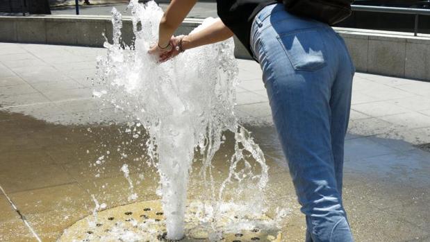 Una transeúnte se refresca por el calor en una fuente en el centro de Alicante