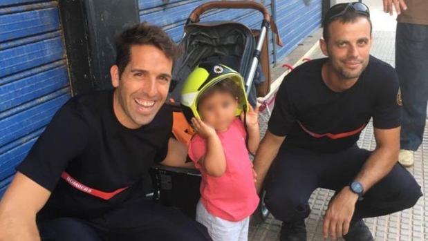 La pequeña, con su casco, con los bomberos que la rescataron