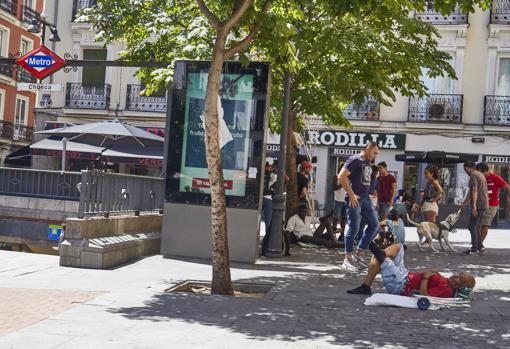 Varias personas descansan tumbados en la plaza de Chueca