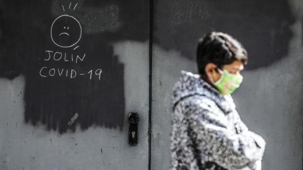 Una transeúnte pasa junto a dibujo sobre el Covid-19 en una calle de Valencia