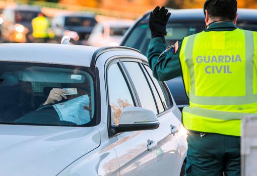 Un guadia civil permite el paso a un conductor en un control