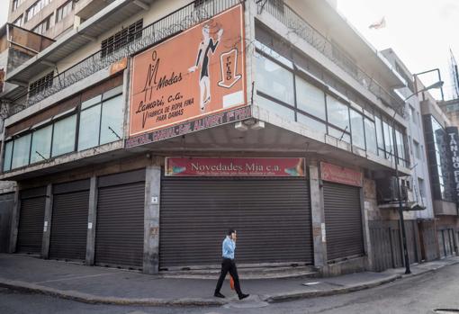 Un hombre camina frente a locales comerciales cerrados