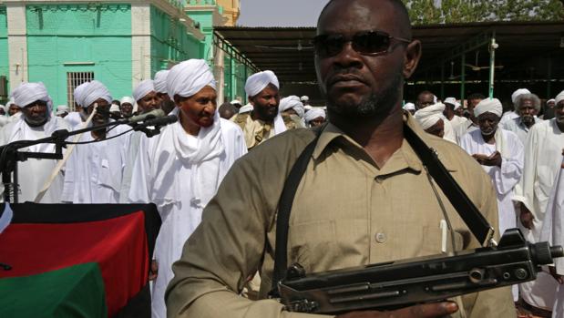 Un oficial armado vigila mientras el imán Sadiq al Mahdi lidera los rezos del Aíd al Fitr, que marca el final del Ramadán, este miércoles, en Omdurmán, Sudán