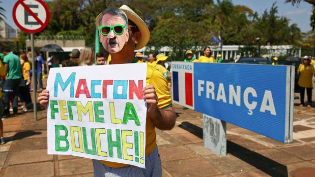 Un simpatizante de Bolsonaro sostiene un cartel con la inscripciÃ³n Â«Macron, cierra la bocaÂ» frente a la embajada francesa en Brasil este domingo