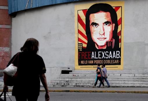 Varias personas pasan frente a un cartel de apoyo a Alex Saab en Caracas