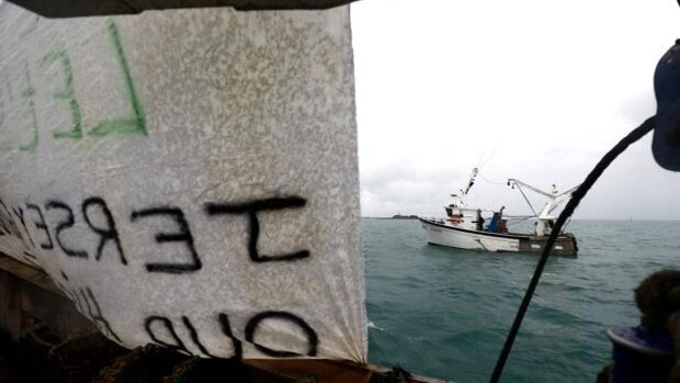Una pancarta cuelga en un barco pesquero francés mientras otros barcos protestan frente al puerto de Saint Helier, cerca de la isla británica de Jersey
