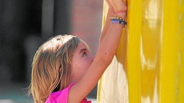 Una niña deposita la bolsa de la basura (con briks, latas, envases de plástico) en el contenedor amarillo