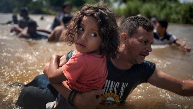 Una niña, inmigrante de Honduras, en brazos de su padre, cruza el río Suchiate, frontera entre Guatelama y México