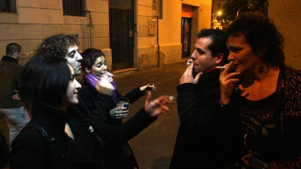 Jóvenes fumando en la puerta de un bar