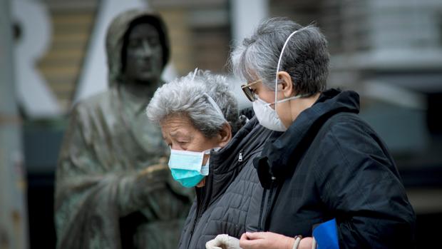Una anciana, protegida con una mascarilla contra el coronavirus, camina por la calle